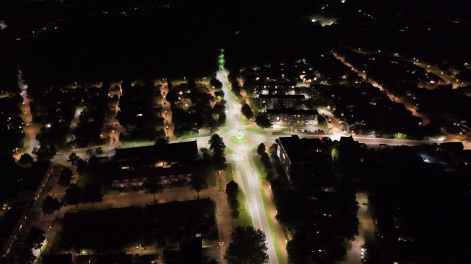 Luchtaufnahme van een verlichte stad bij nacht met straten en huizen.